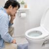 マンションでトイレの流れが悪い原因を調べている男
